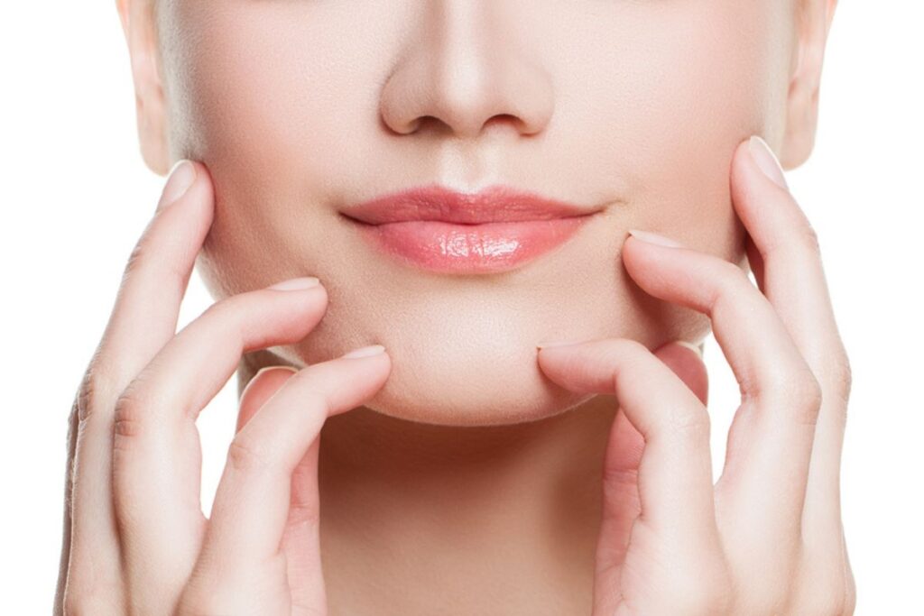Close-up of a woman's lower face and hands, highlighting the importance of personalized dermal filler treatment for facial symmetry.