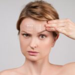 Woman pointing to forehead with diagram lines, illustrating brow lift concept and upper facial rejuvenation options.